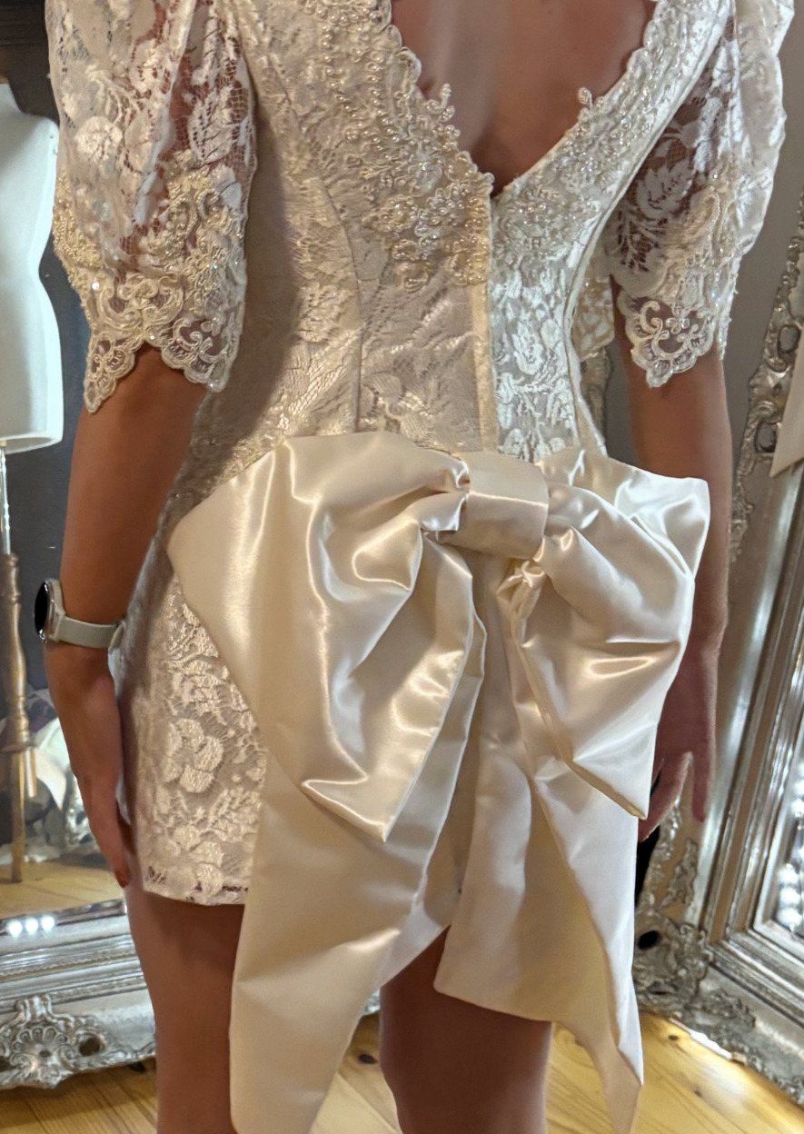 Back view of a vintage lace mini dress with satin bow detail after heirloom alterations by Jacqui