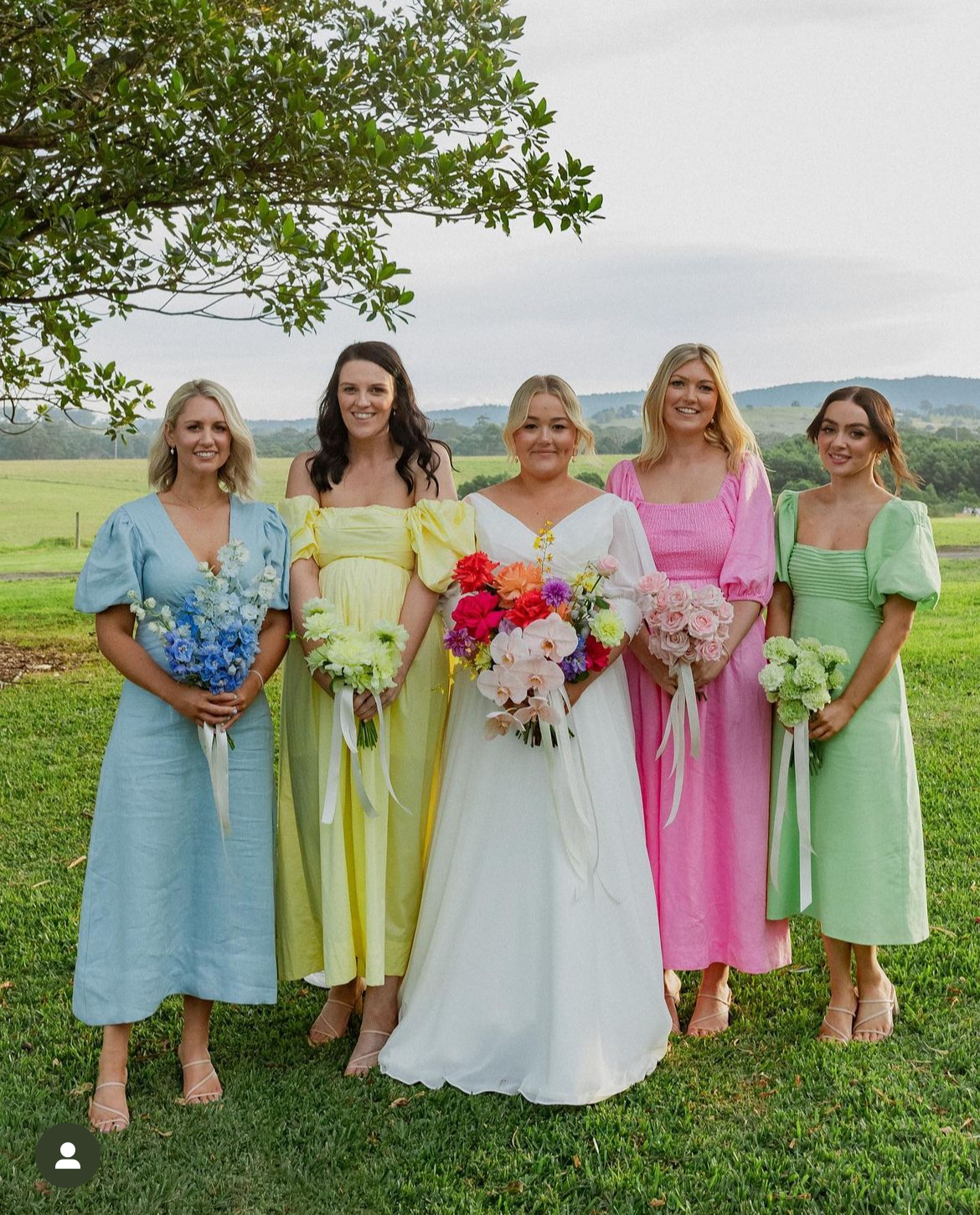 Bridesmaids in pastel puff-sleeve dresses in blue, yellow, pink and green with bride, altered on the NSW South Coast