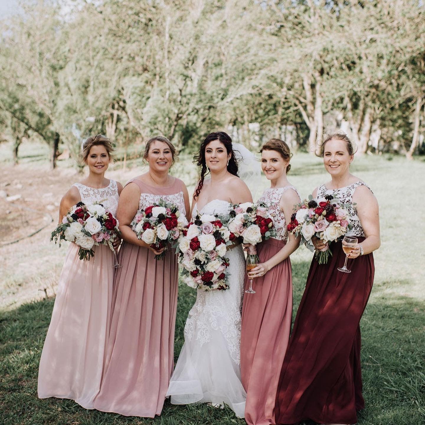 Bridesmaids in mixed pink and burgundy lace-bodice gowns with bride, coordinated fittings by Jacqui